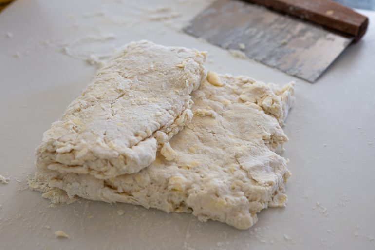 Biscuit Dough folded on a white surface.
