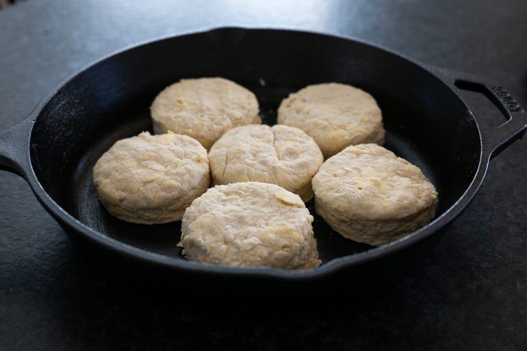 Raw biscuits in a cast iron skillet.