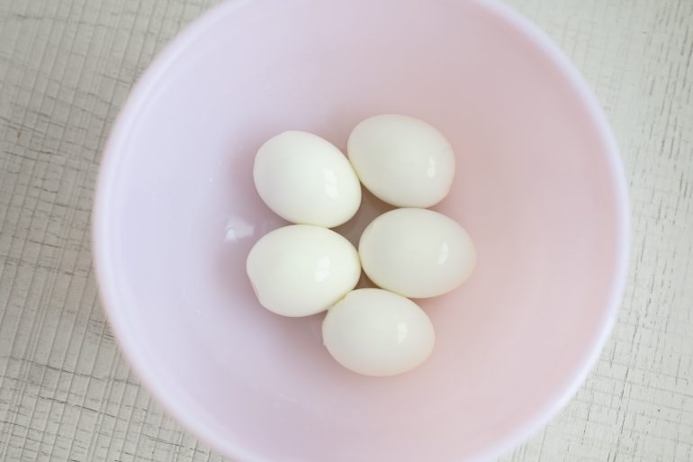 5 boiled and peeled eggs in a pink bowl. The eggs peeled using the America's Test kitchen method.