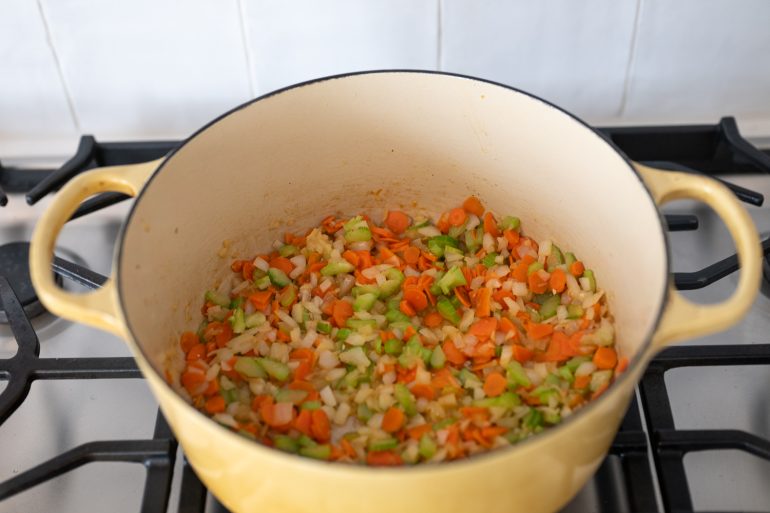 Carrots, celery, and onion in a yellow pot.