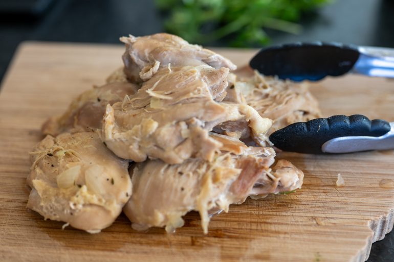 Chicken on a cutting board. You can see tongs to the side.