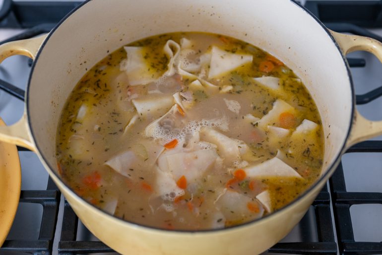 Dumplings simmering in a pot on a stove top.