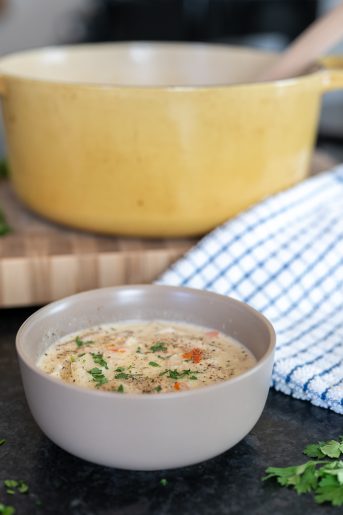Photo of a bowl of soup with a yellow pot in the background.
