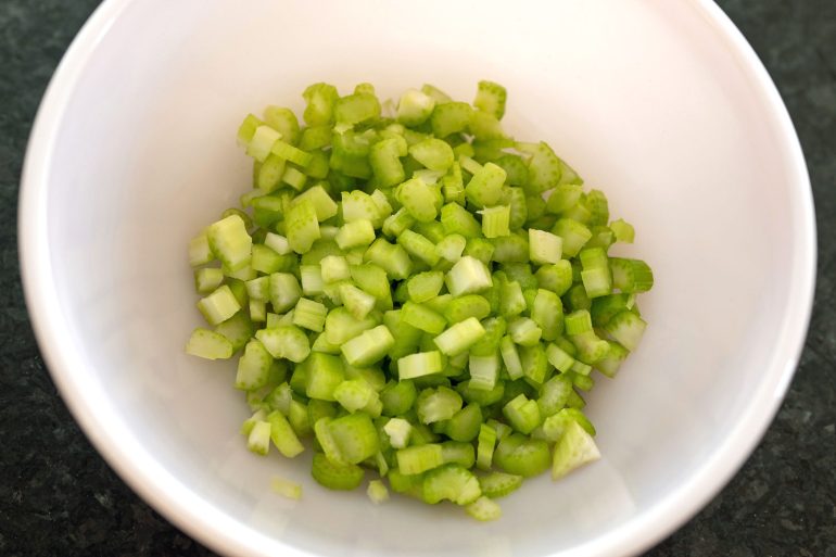 A pink bowl with chopped celery in it.