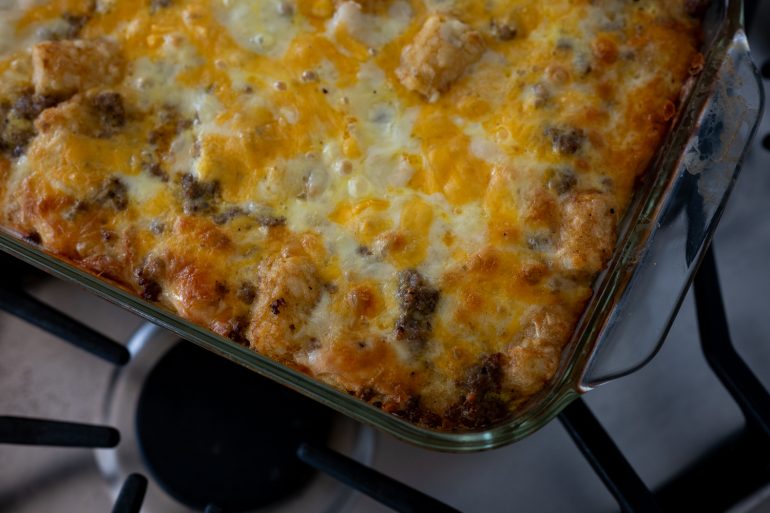 A close up of a tater tot breakfast casserole that has been cooked. It looks cheesy and delicious.