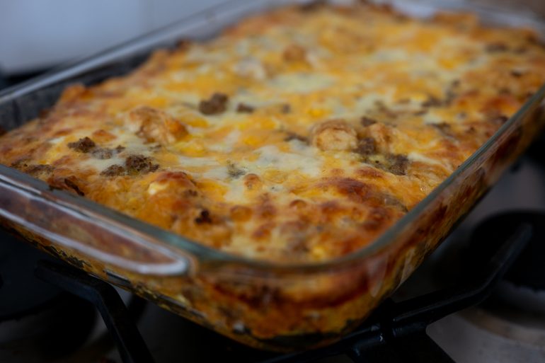 A close up of a tater tot breakfast casserole that has been cooked. It looks cheesy and delicious.