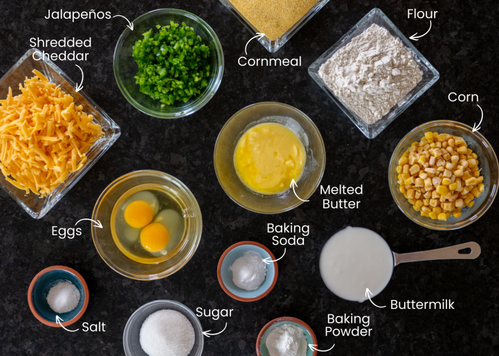 Ingredients for Jalapeno Cheddar Cornbread shown on a black background from above. The ingredients are all labeled.