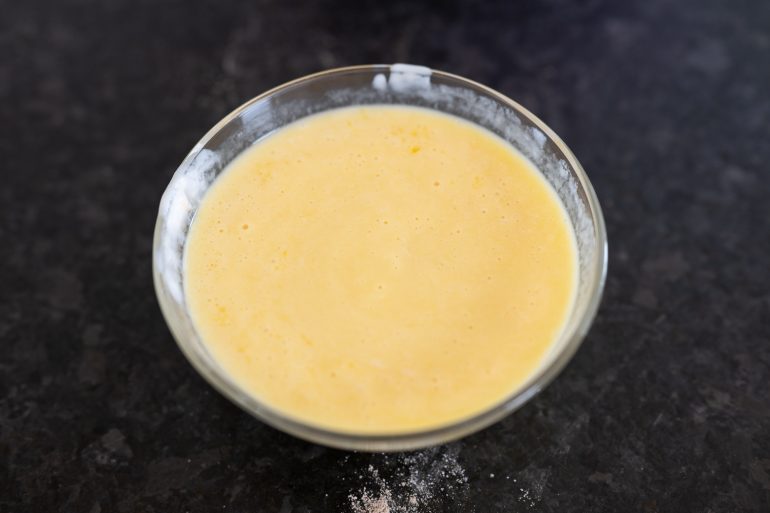 Eggs, buttermilk, baking soda, and vanilla mixed in a small bowl ready to use in an Old-Fashioned Texas Sheet Cake batter.