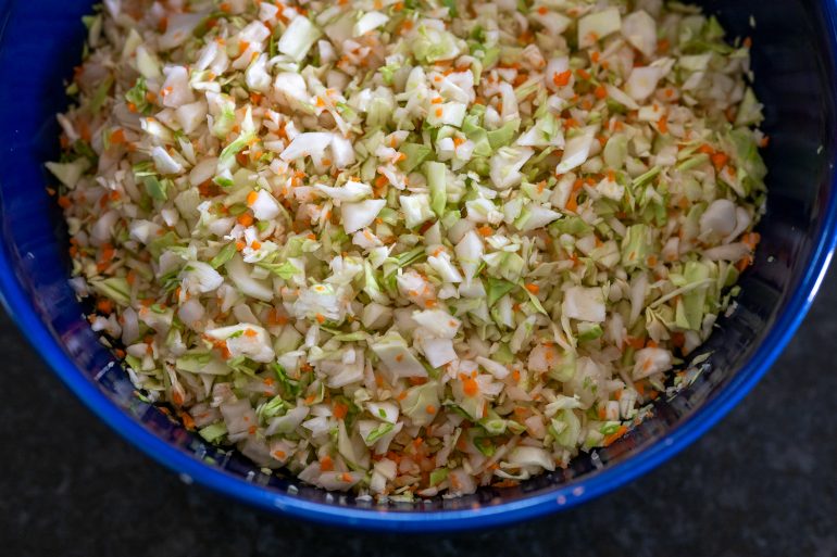 A shot of cabbage, carrot, and onion chopped small and shown from above. This is in preparation for the KFC style coleslaw copycat recipe.