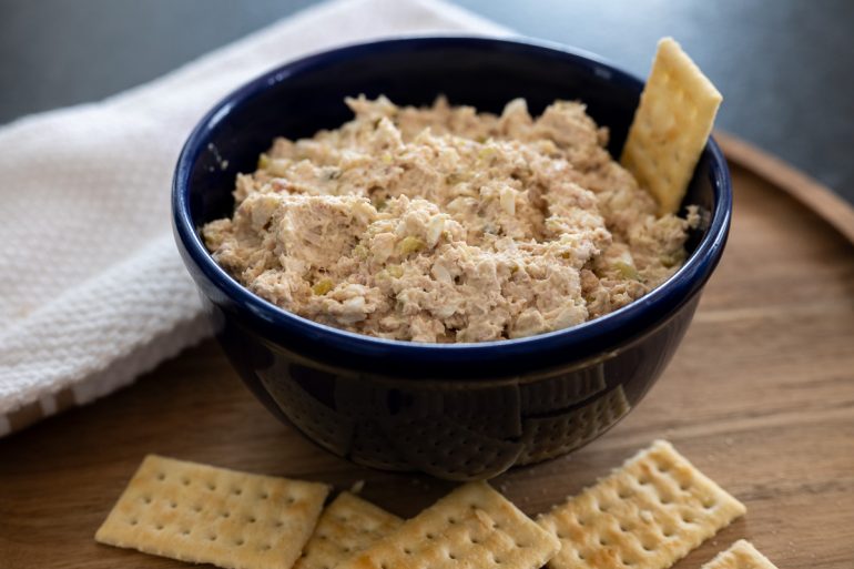 A bowl of dip with crackers.