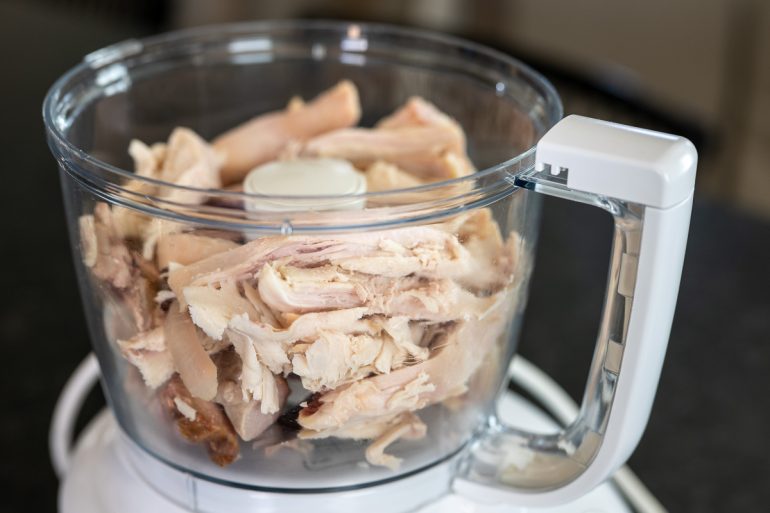 Chunks of smoked turkey in a food processor about to be processed.