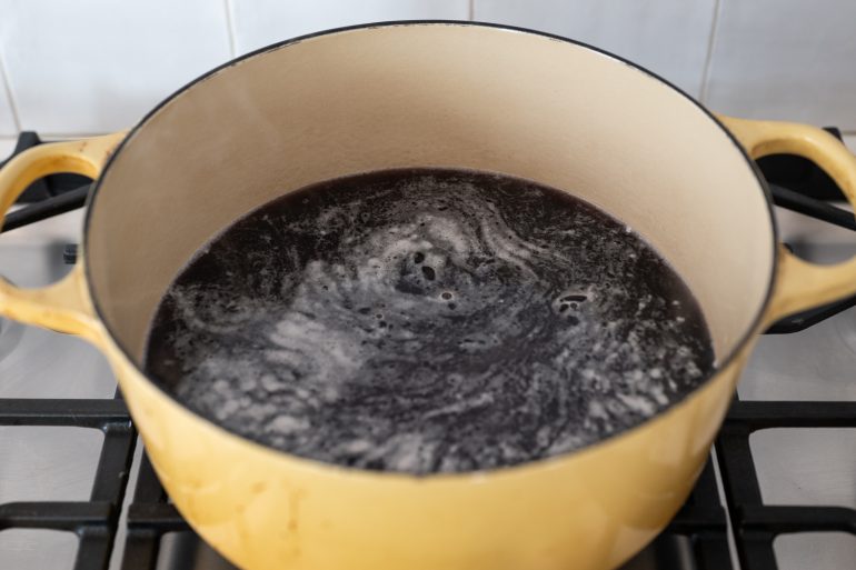 A large yellow pot with simmering liquid and beans inside. 