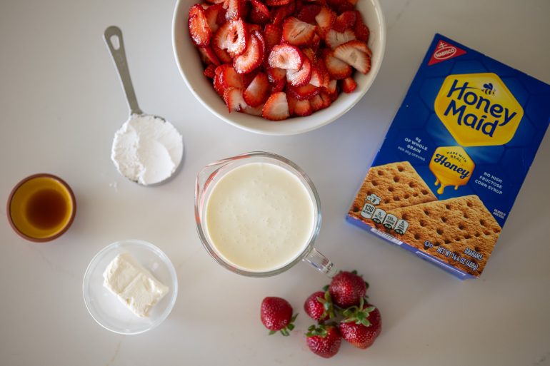 The ingredients for a strawberry icebox pie are shown individual from above. 