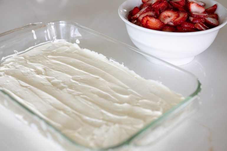 whipped cream spread over graham crackers as one of the layers on a strawberry icebox pie. 